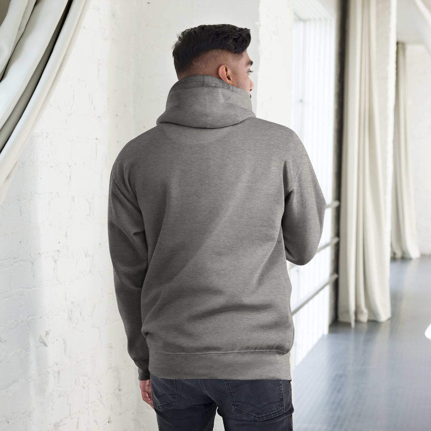 Man wearing unisex premium carbon grey hoodie seen from back in bright modern indoor space
