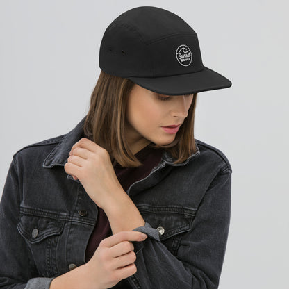 Woman wearing black 5-panel cap with white Sunset Wave Co logo and black denim jacket