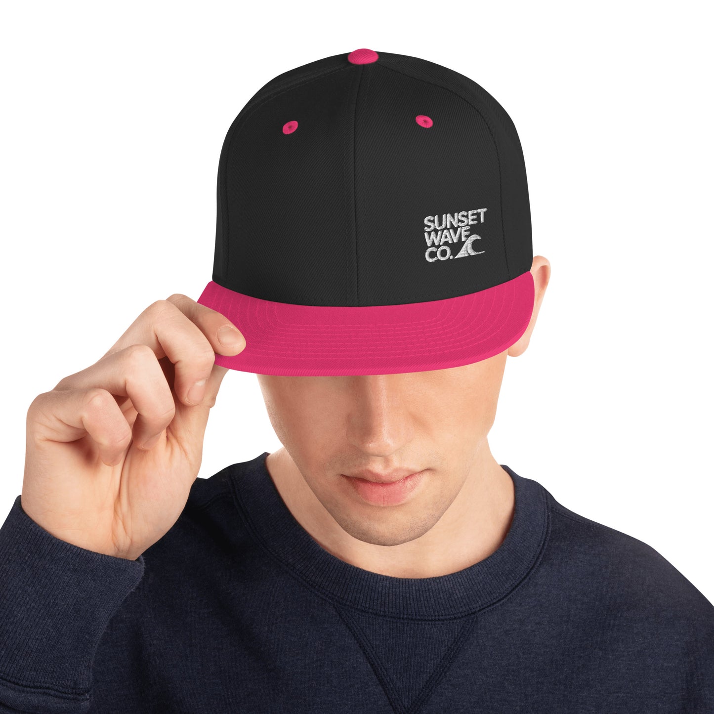 Black snapback hat with neon pink brim and accents, embroidered 'Sunset Wave Co.' logo, worn by man
