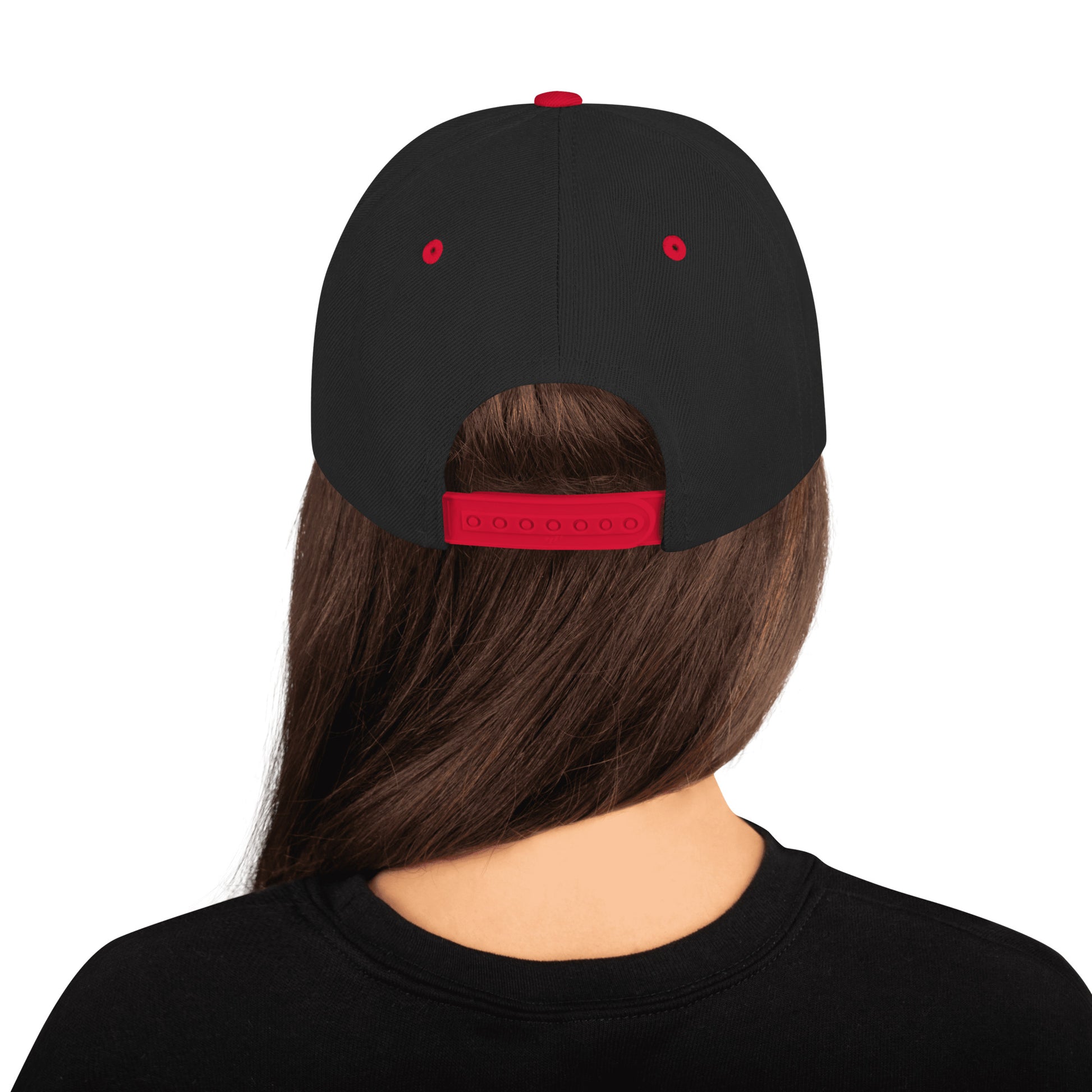 Back view of person with long brown hair wearing black snapback cap with red adjustable strap and red eyelets