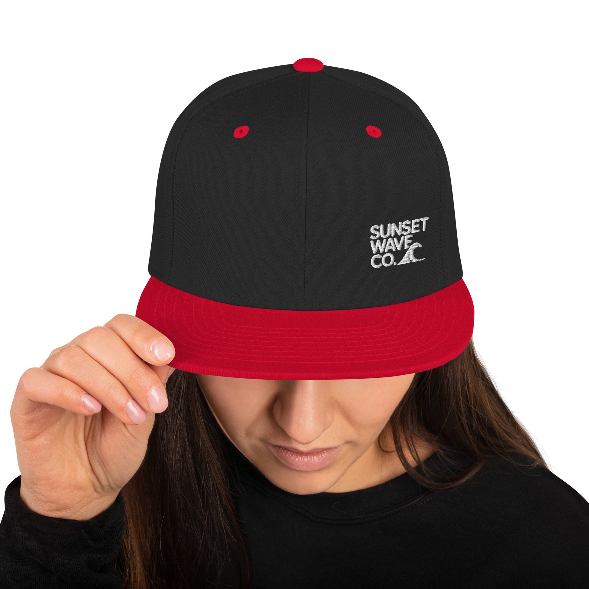 Black and red classic snapback cap with Sunset Wave Co. logo worn by woman looking down