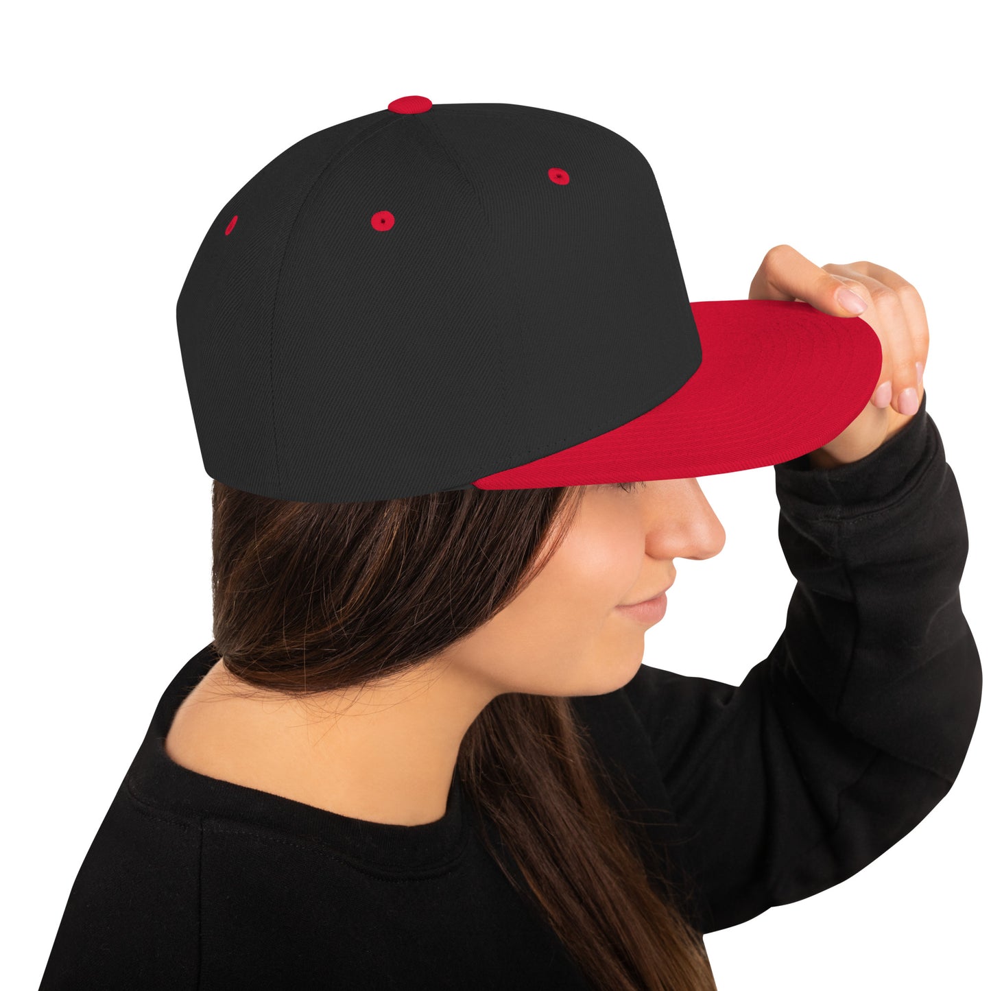 Woman wearing black snapback cap with red brim adjusting the hat on a white background