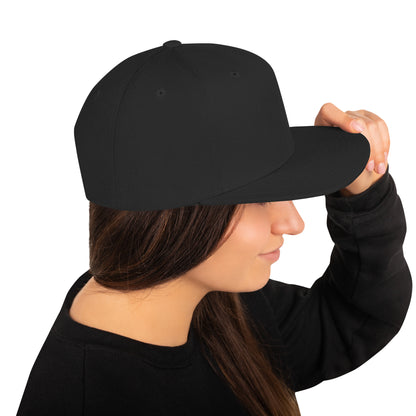 Woman wearing black classic snapback hat holding the brim on white background