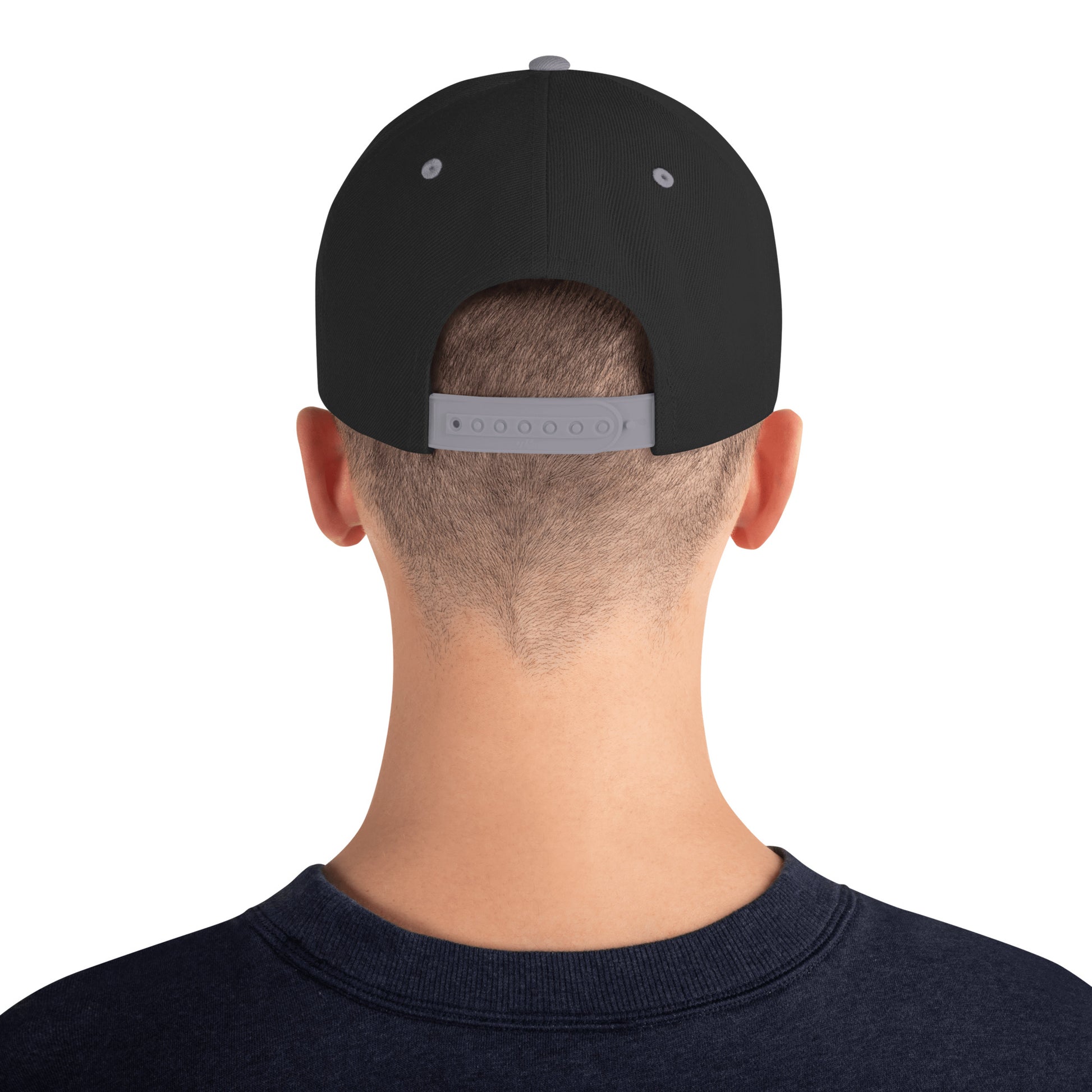 Back view of man wearing black snapback hat with silver adjustable strap and navy shirt