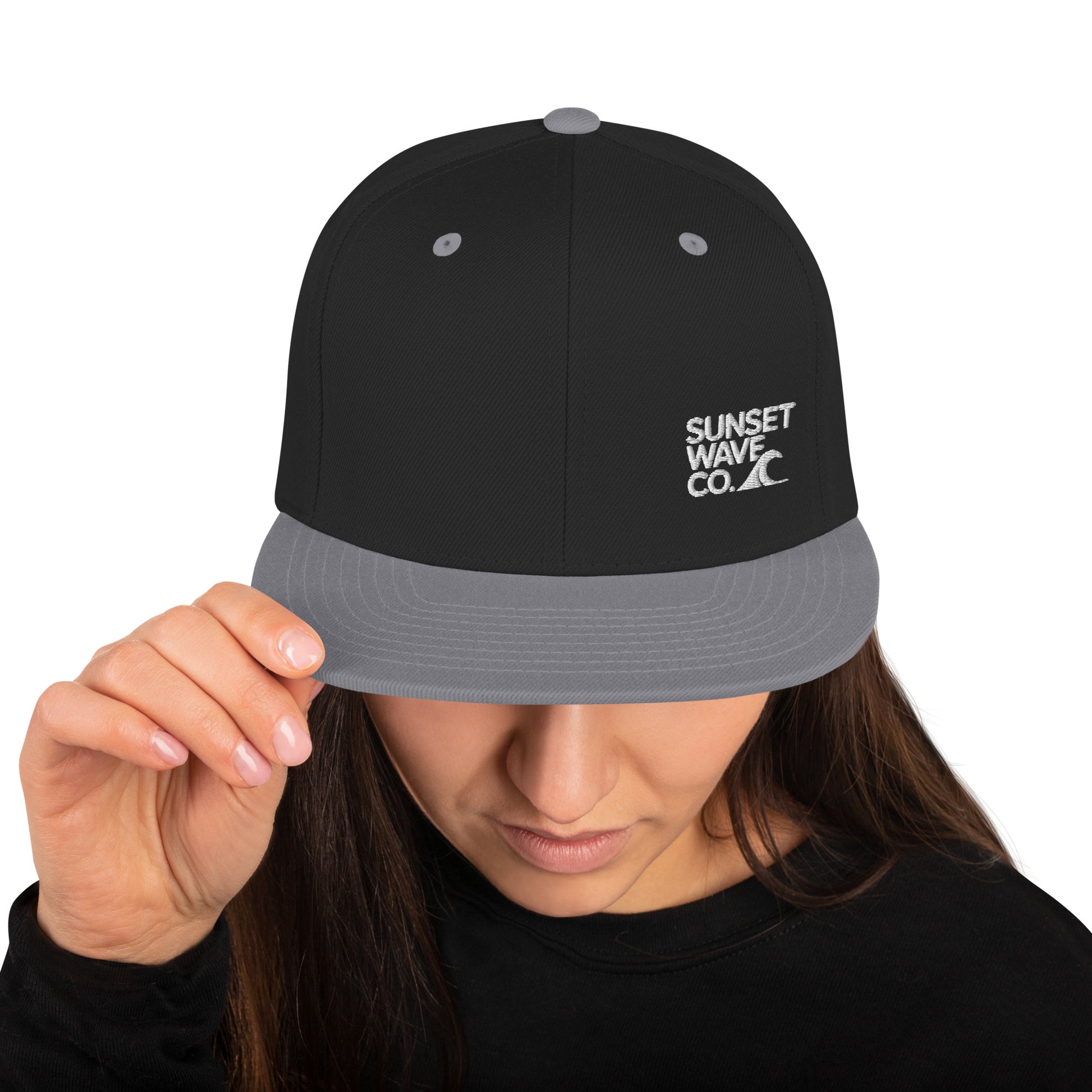 Woman wearing black and gray snapback hat with white Sunset Wave Co. logo