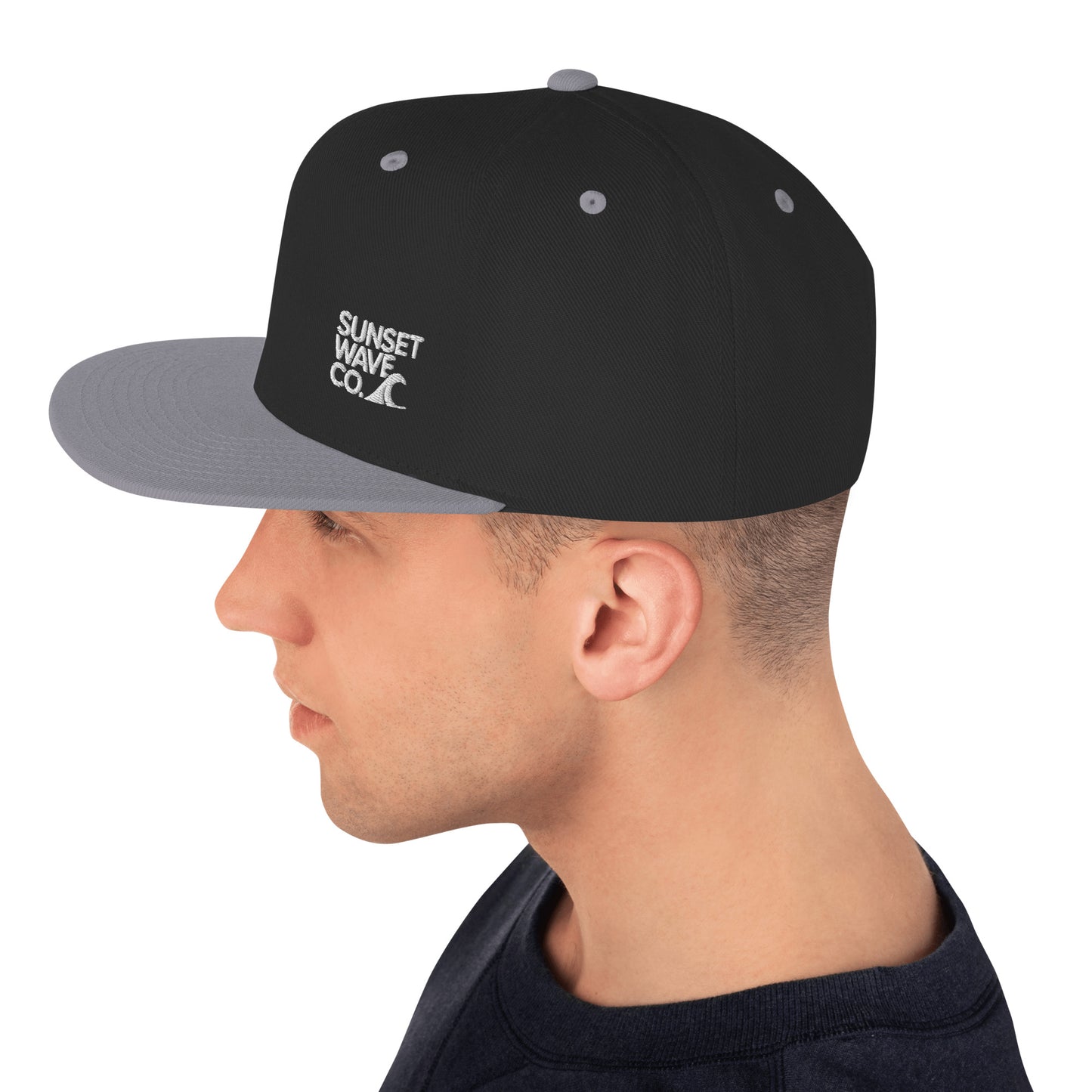 Side view of man wearing black and silver classic snapback hat with Sunset Wave Co logo