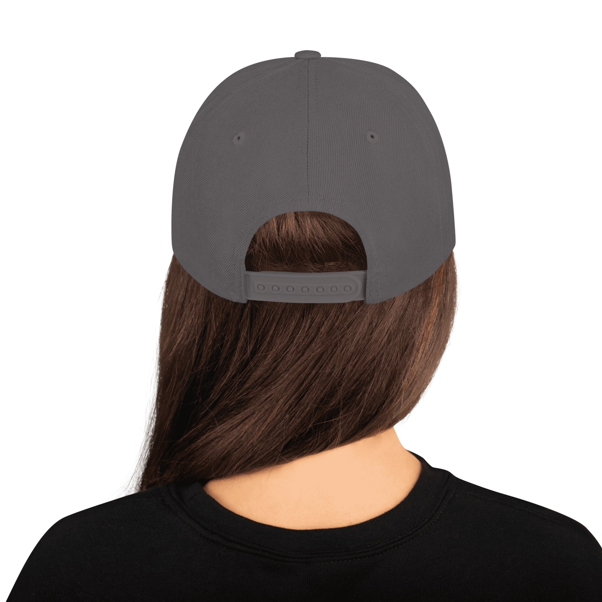 Back view of a dark grey classic snapback cap worn by a person with long brown hair in a black shirt