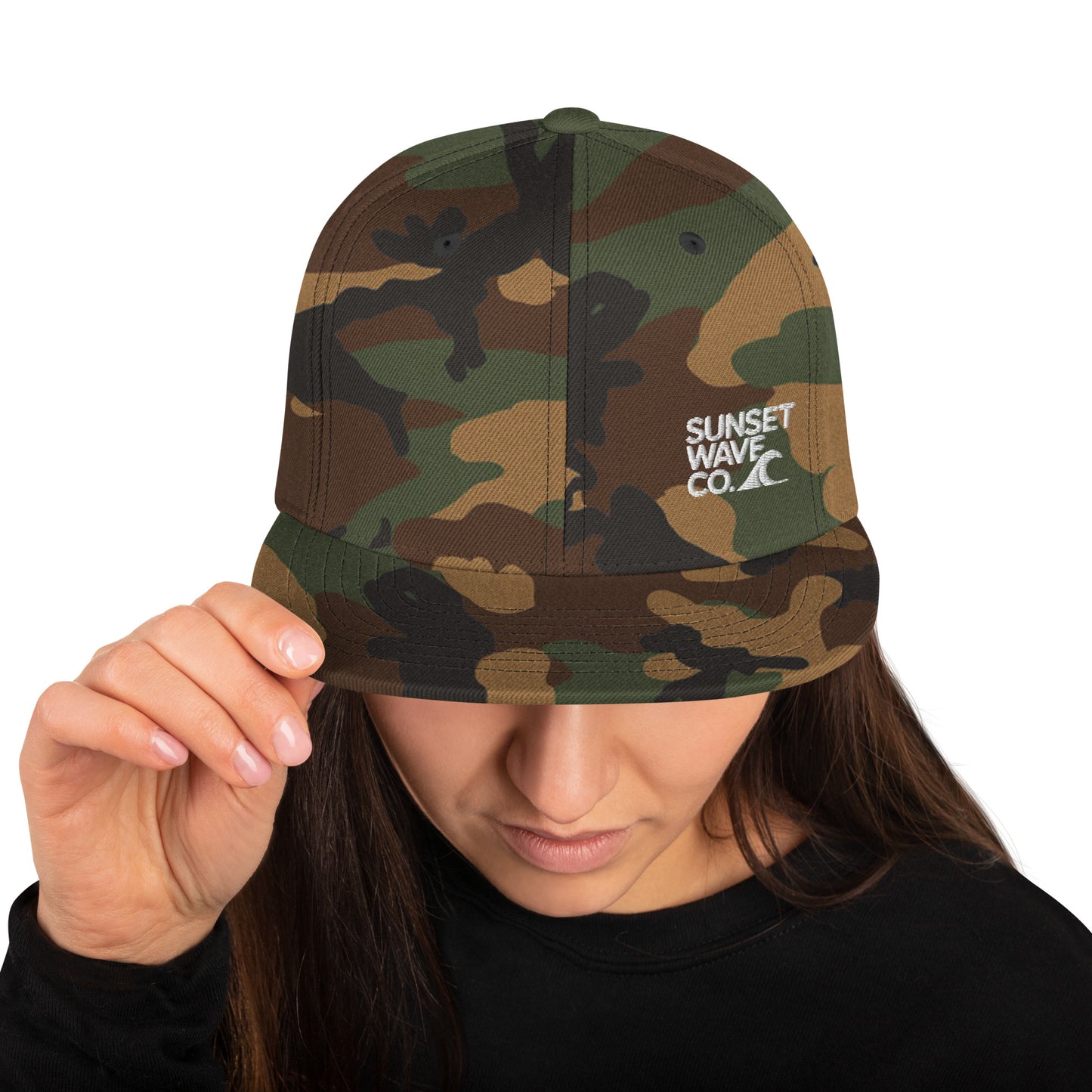 Woman wearing green camo snapback hat with white Sunset Wave Co. logo