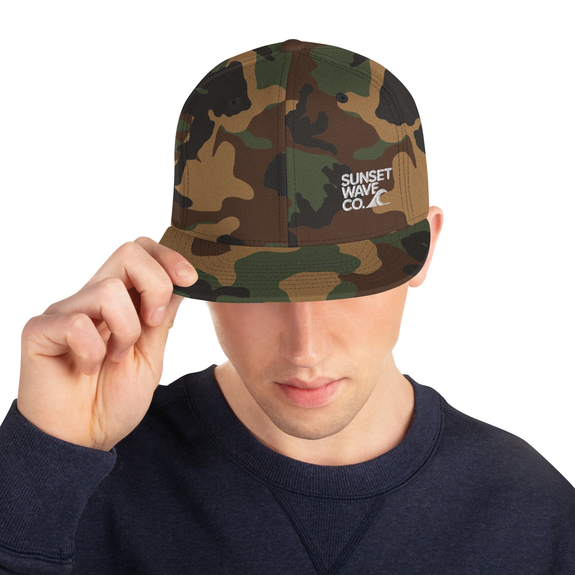 Man wearing green camo classic snapback hat with white Sunset Wave Co. logo on front