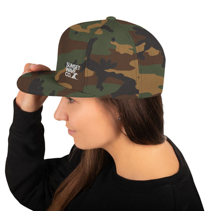 Woman wearing a green camo classic snapback hat with Sunset Wave Co logo on side