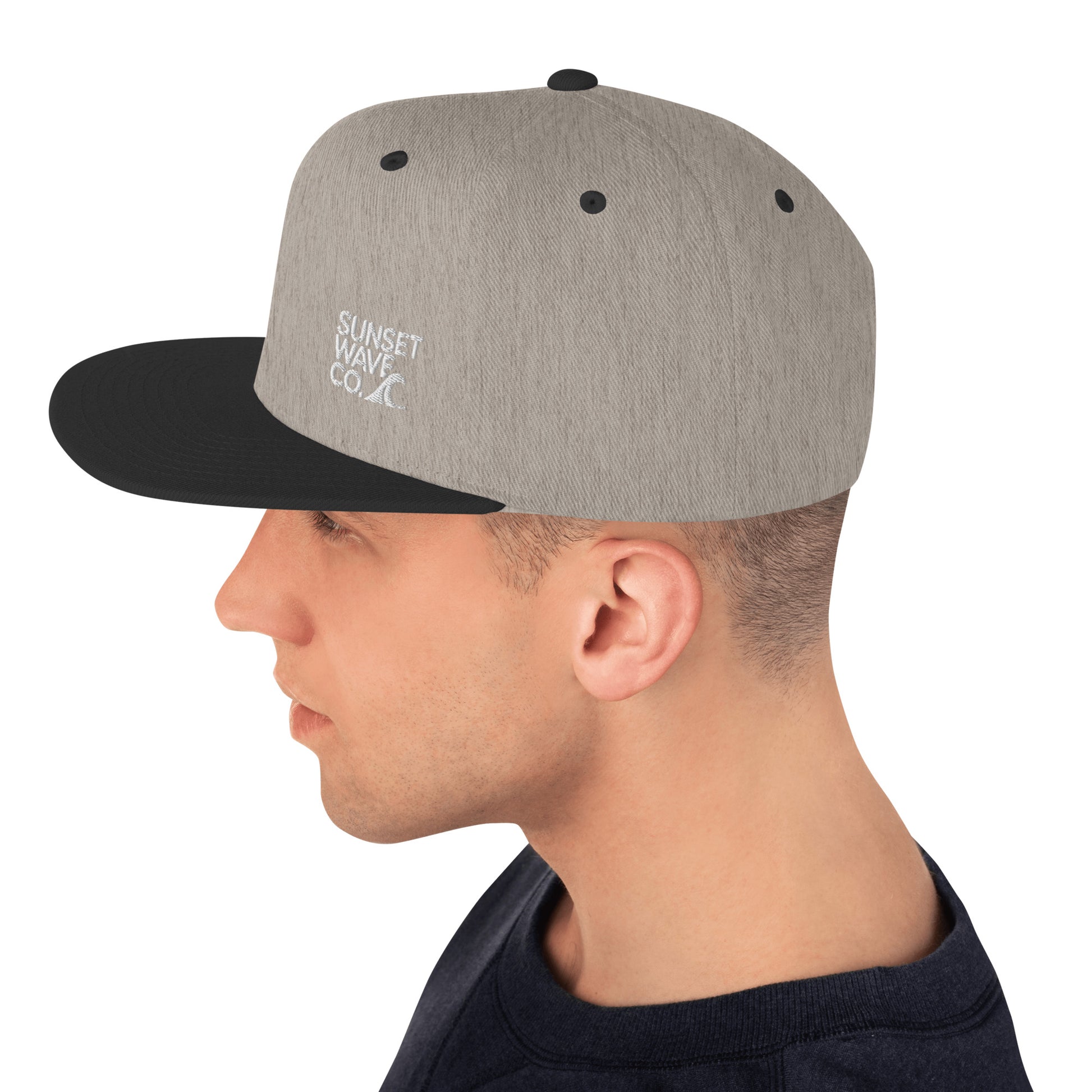 Side view of man wearing heather gray and black classic snapback hat with Sunset Wave Co. logo