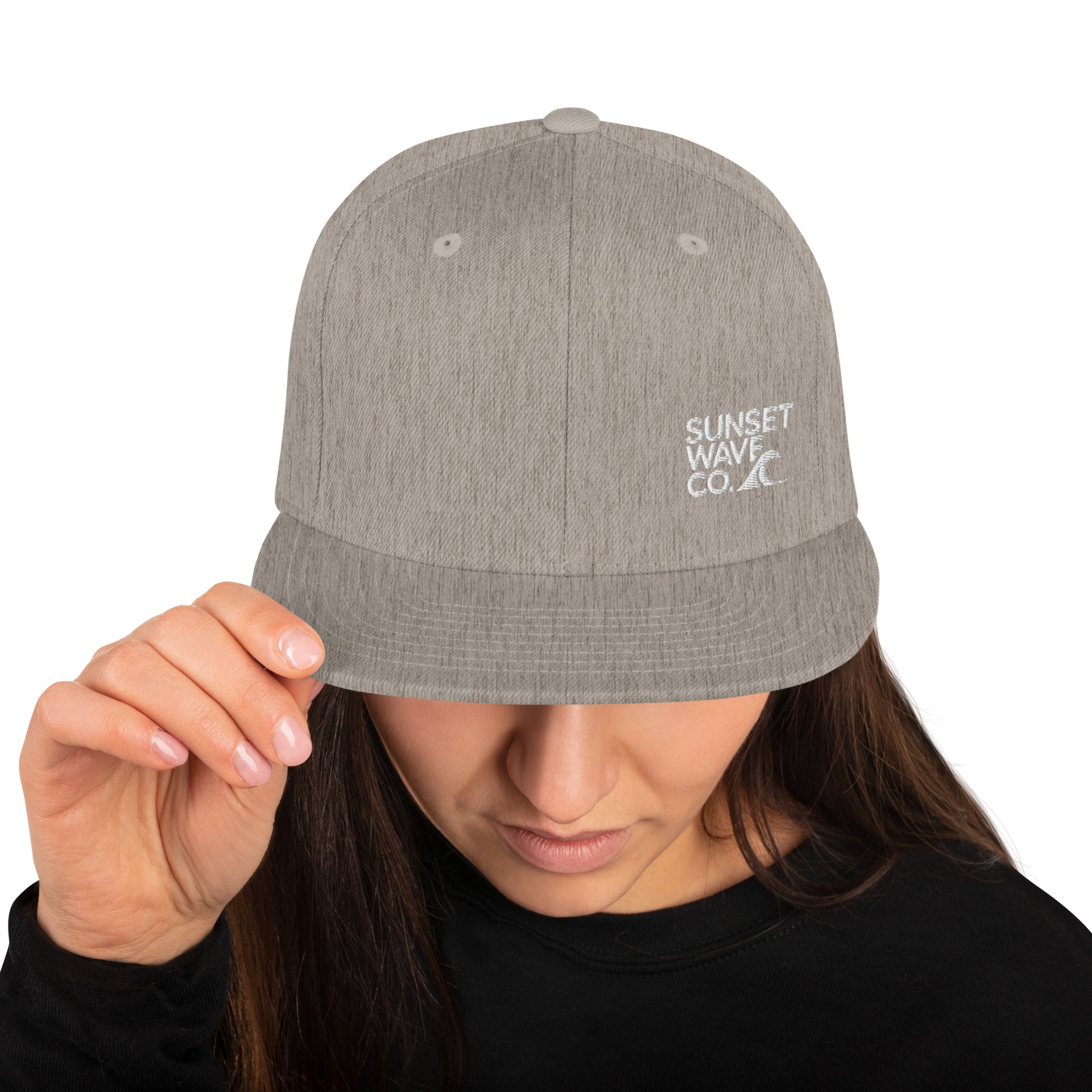 Heather grey classic snapback cap with white Sunset Wave Co. logo worn by person in black shirt