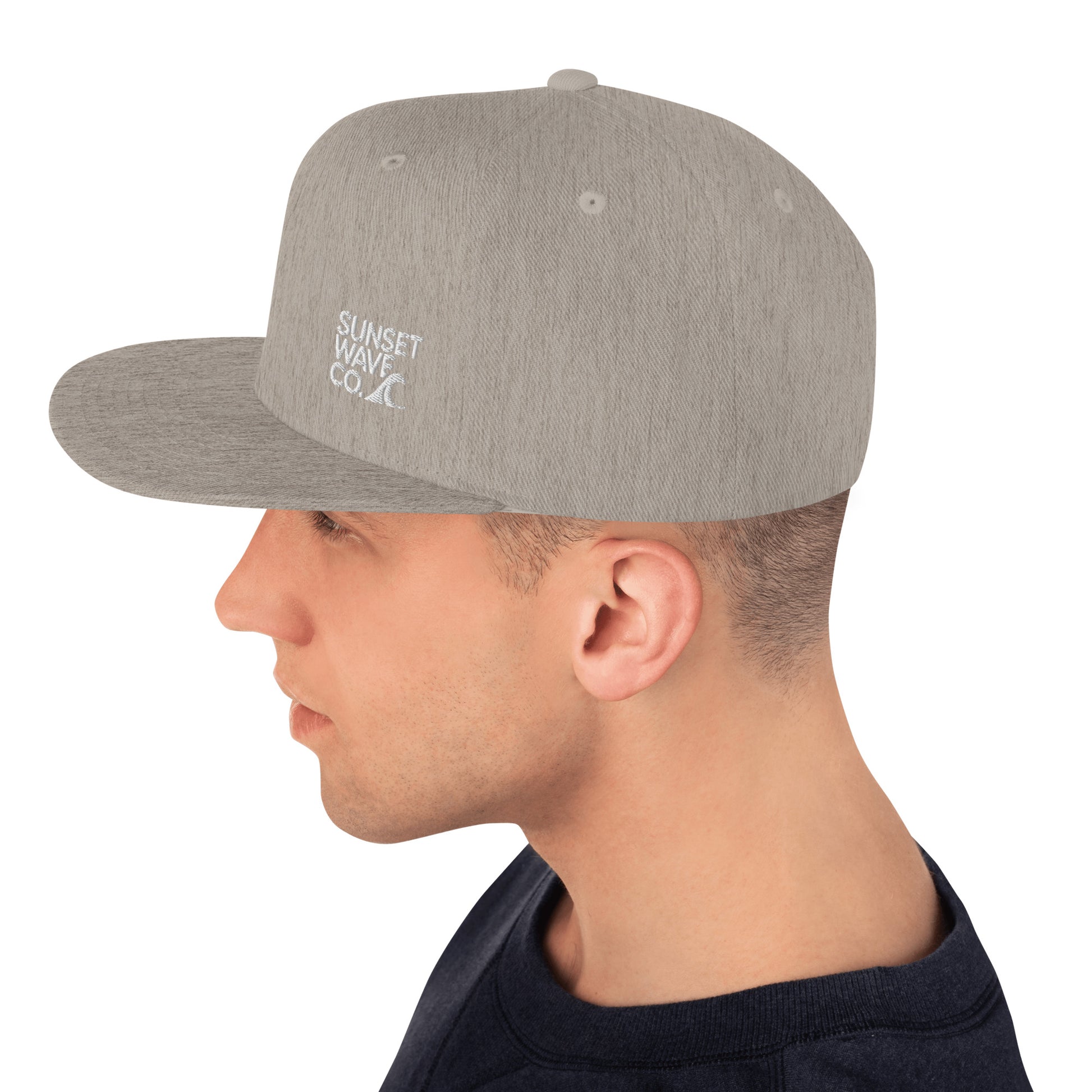 Heather grey classic snapback cap with Sunset Wave Co. white logo worn by man in navy shirt