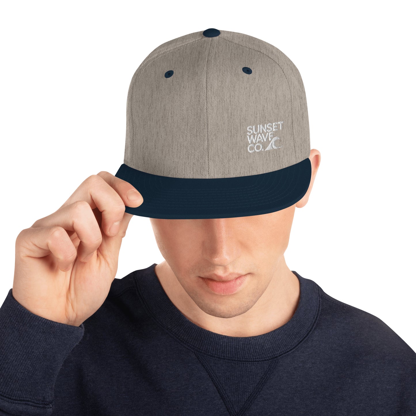 Man wearing classic snapback hat in heather grey with navy brim and Sunset Wave Co. logo