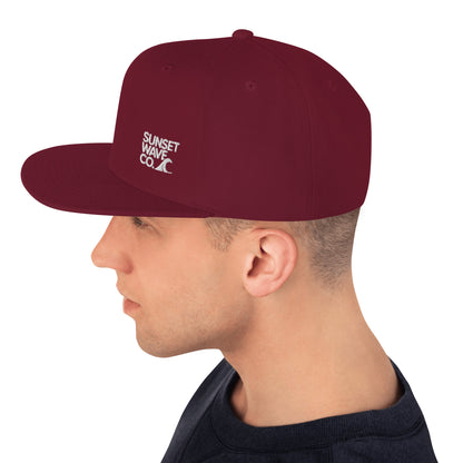 Side view of man wearing maroon classic snapback cap with white Sunset Wave Co. logo