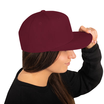 Woman wearing a classic maroon snapback hat and black sweatshirt, holding the brim