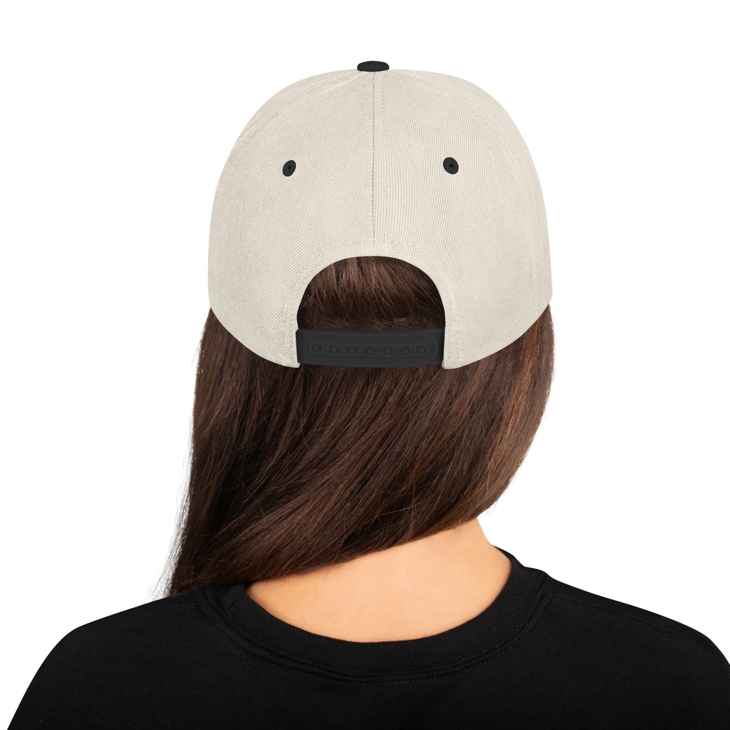 Back view of woman wearing a natural beige snapback cap with black adjustable strap and black shirt