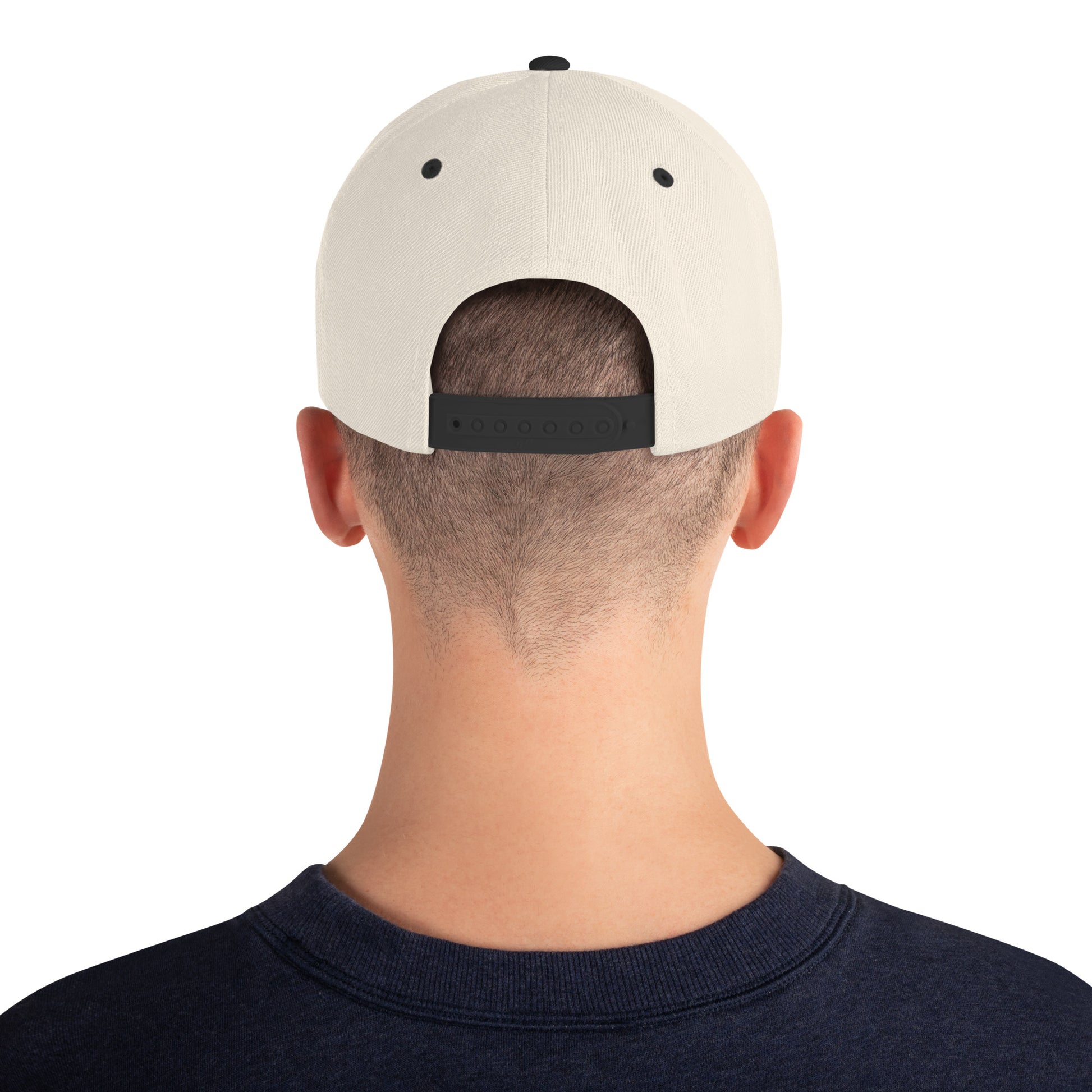 Back view of person wearing a natural color snapback cap with black adjustable strap and navy shirt