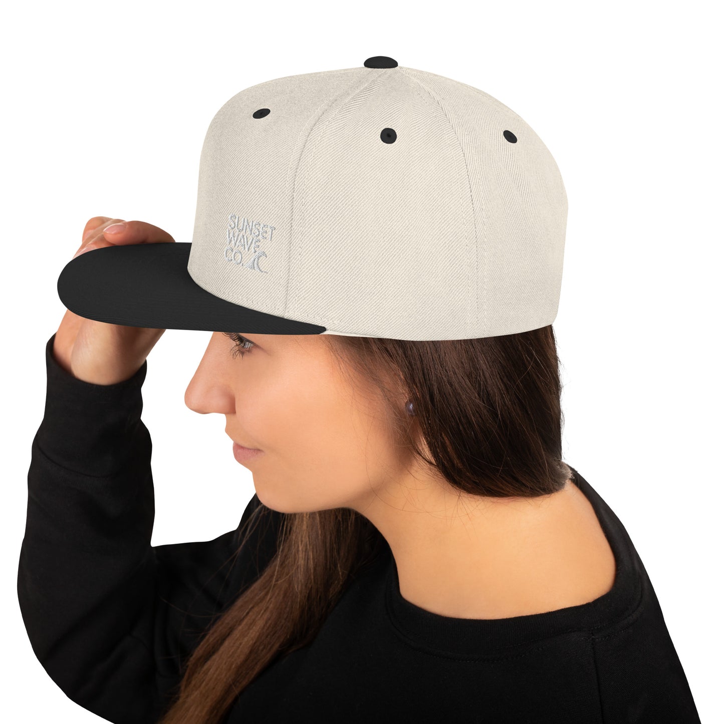 Woman wearing natural color and black snapback cap with Sunset Wave Co. logo on the side