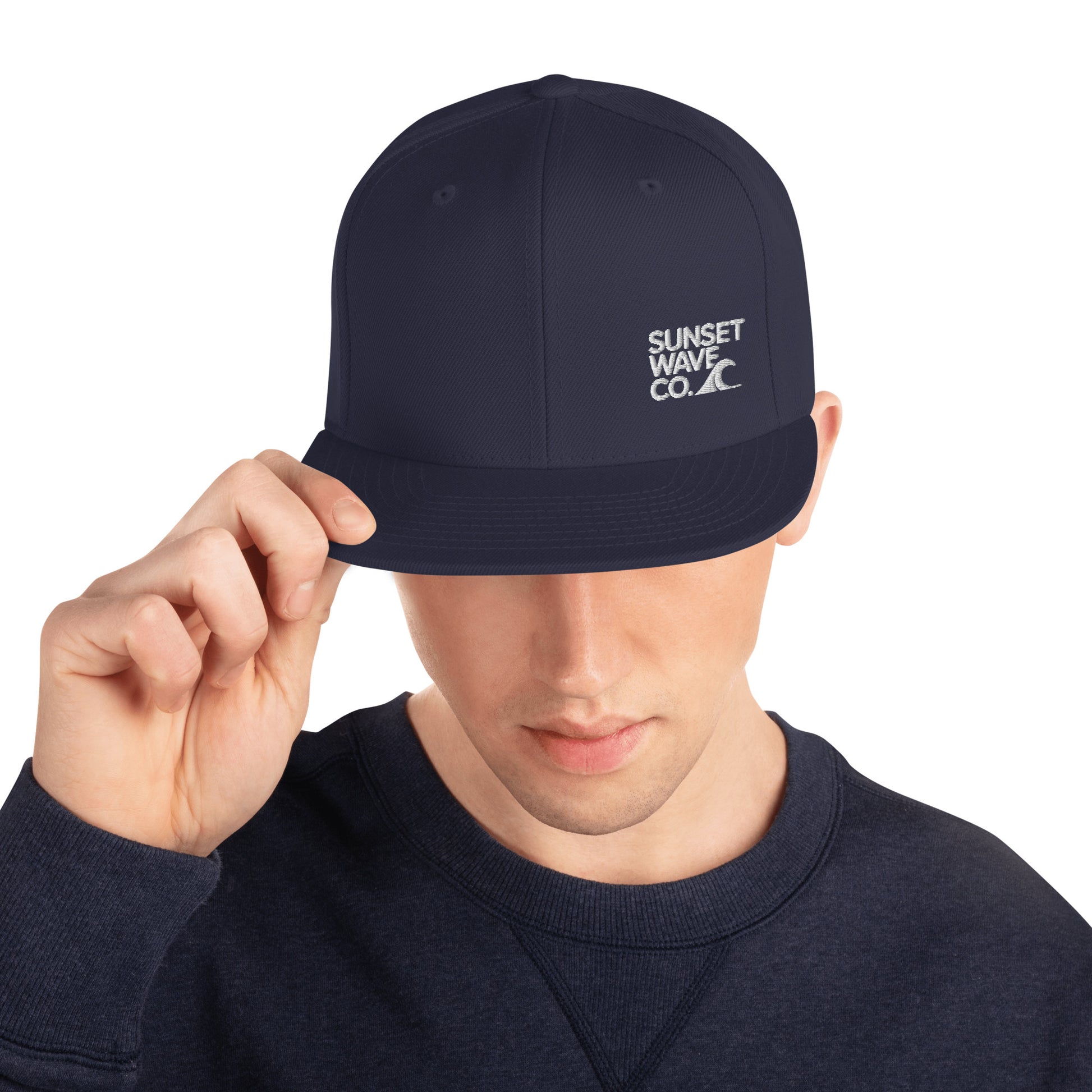 Man wearing navy blue snapback hat with white Sunset Wave Co. logo and navy sweatshirt