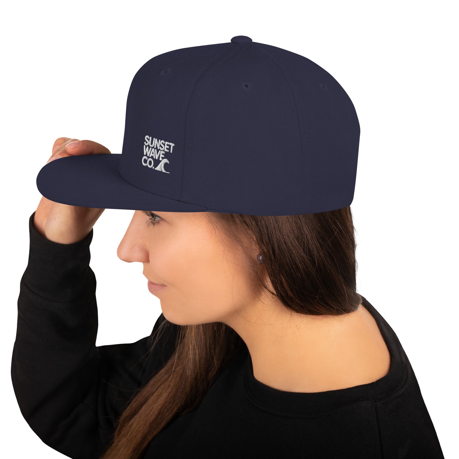 Woman wearing navy classic snapback hat with Sunset Wave Co. logo and wave icon