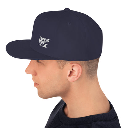 Man wearing navy classic snapback hat with white Sunset Wave Co. logo on side