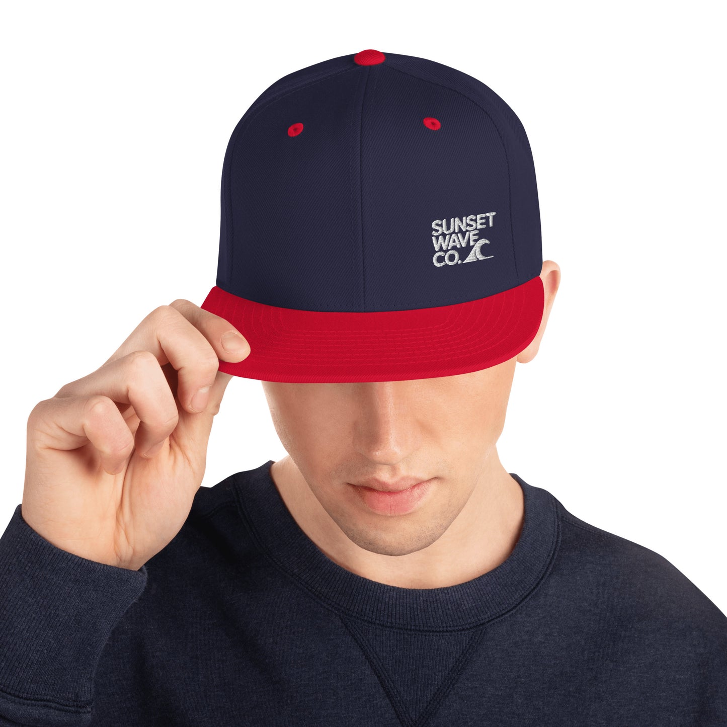 Man wearing classic navy and red snapback cap with Sunset Wave Co. logo and wave graphic