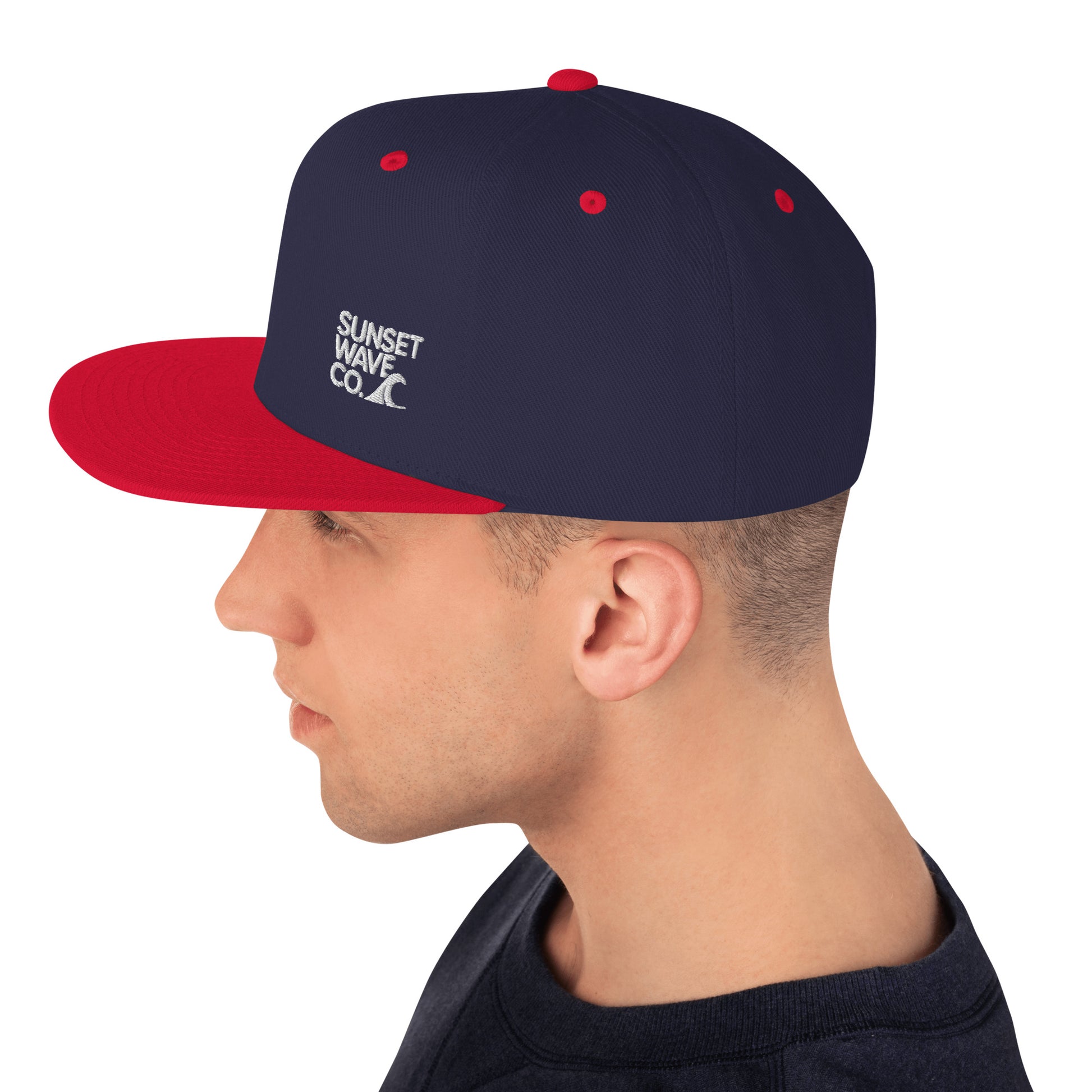 Man wearing navy blue and red classic snapback cap with Sunset Wave Co. logo on side