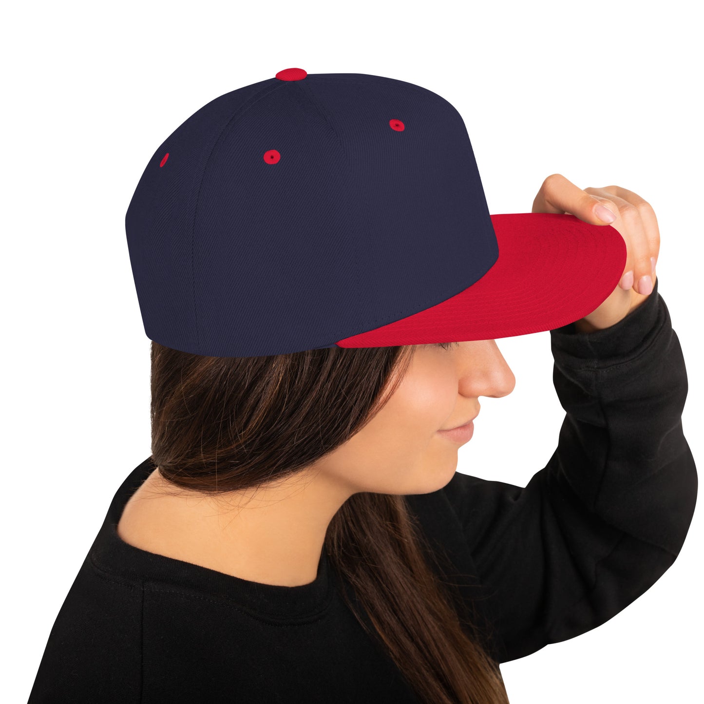 Person wearing navy blue and red classic snapback cap holding the brim