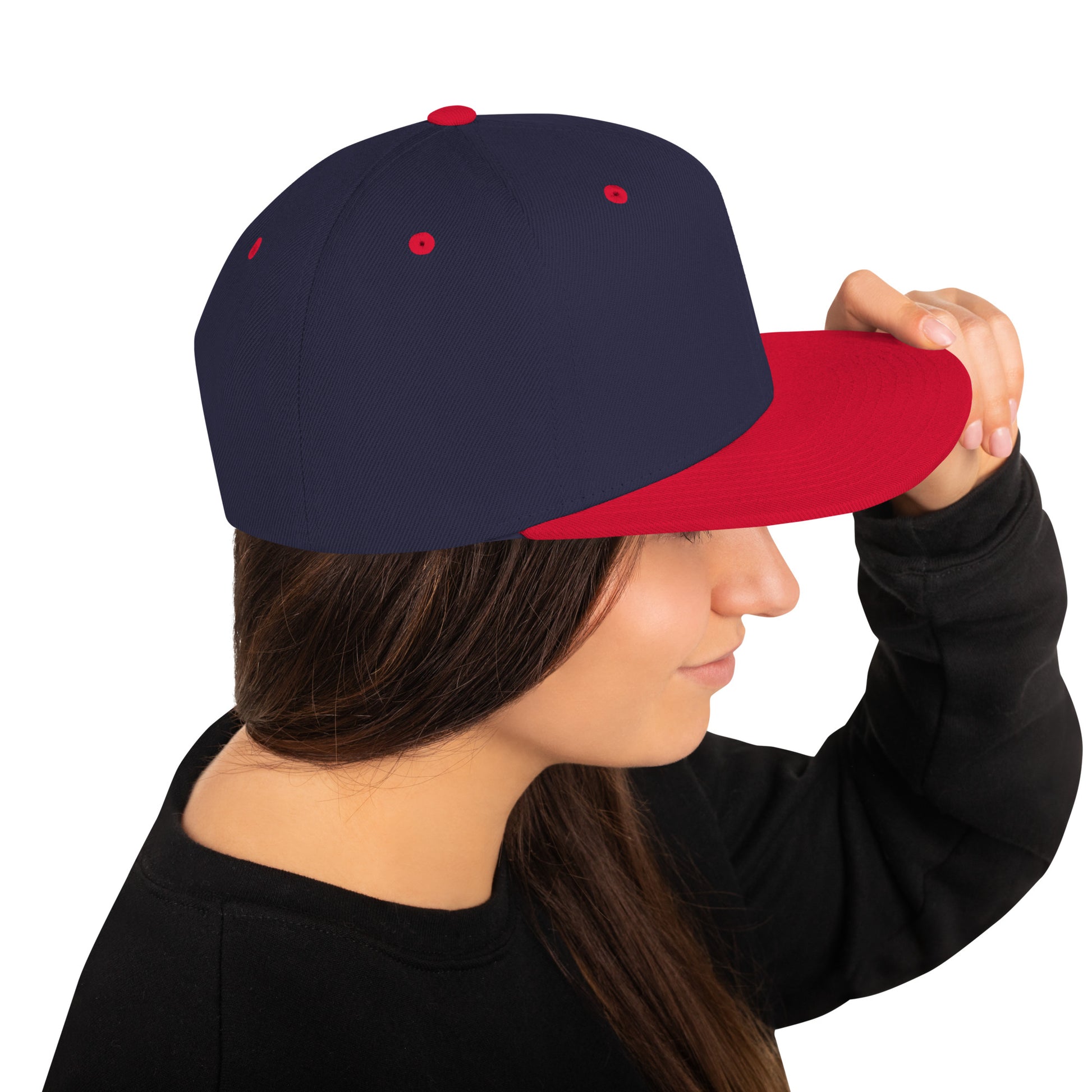 Person wearing navy blue and red classic snapback cap holding the brim