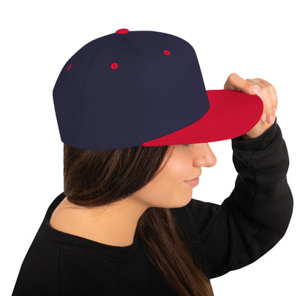 Person wearing navy blue and red classic snapback cap holding the brim