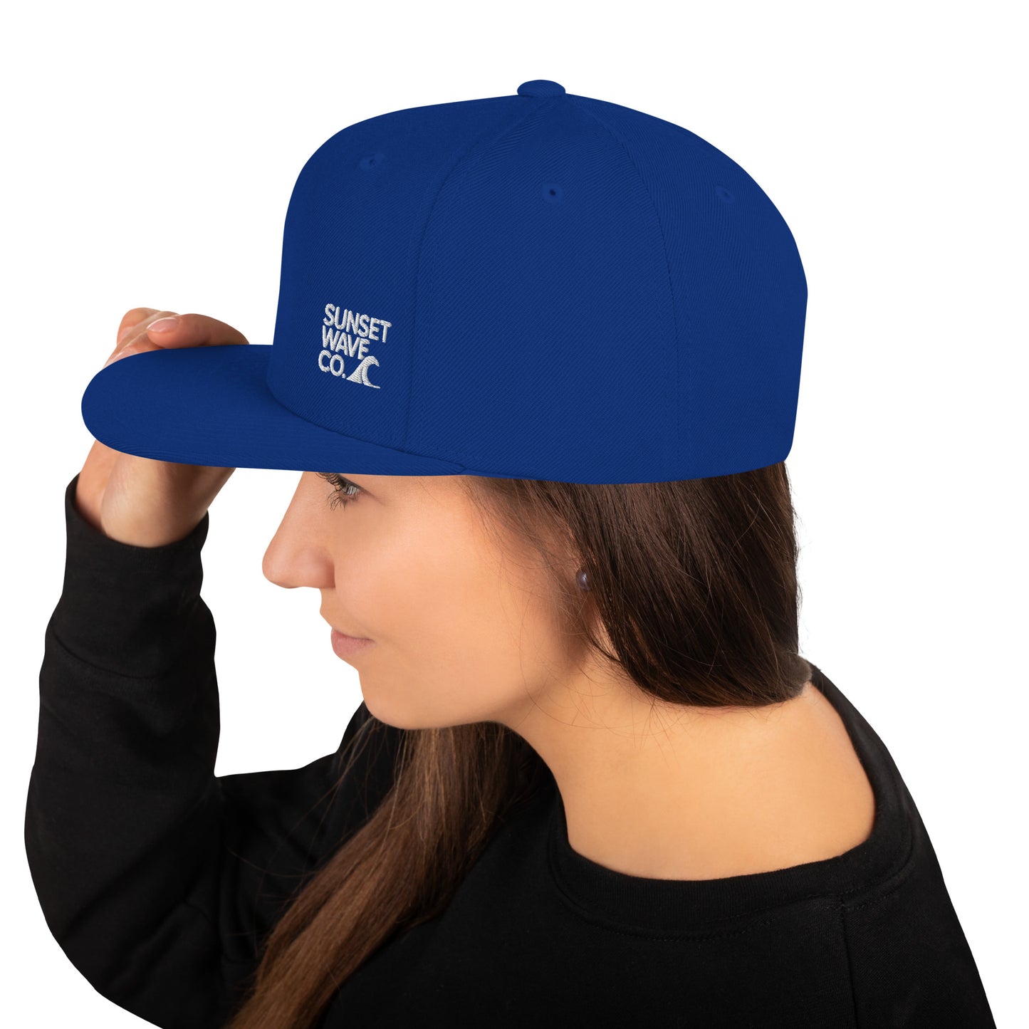 Woman wearing royal blue classic snapback hat with white Sunset Wave Co. logo on side