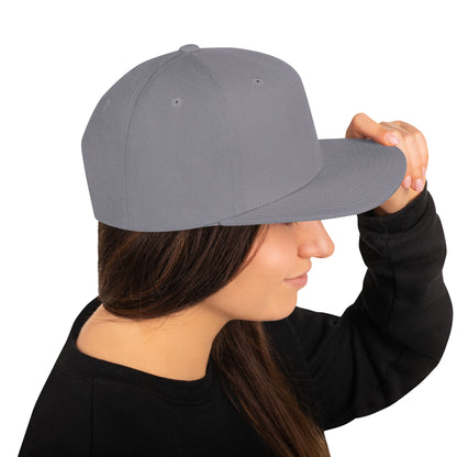 Woman wearing a classic silver snapback cap with flat brim, holding the brim with her hand