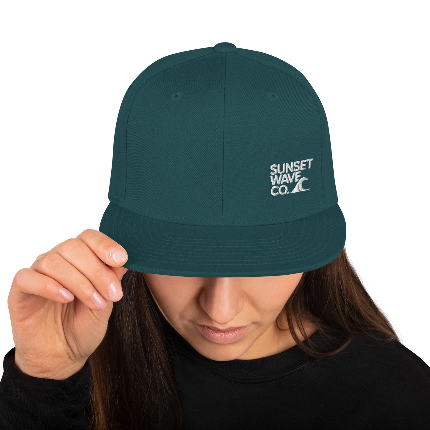Woman wearing dark green classic snapback hat with white Sunset Wave Co. logo