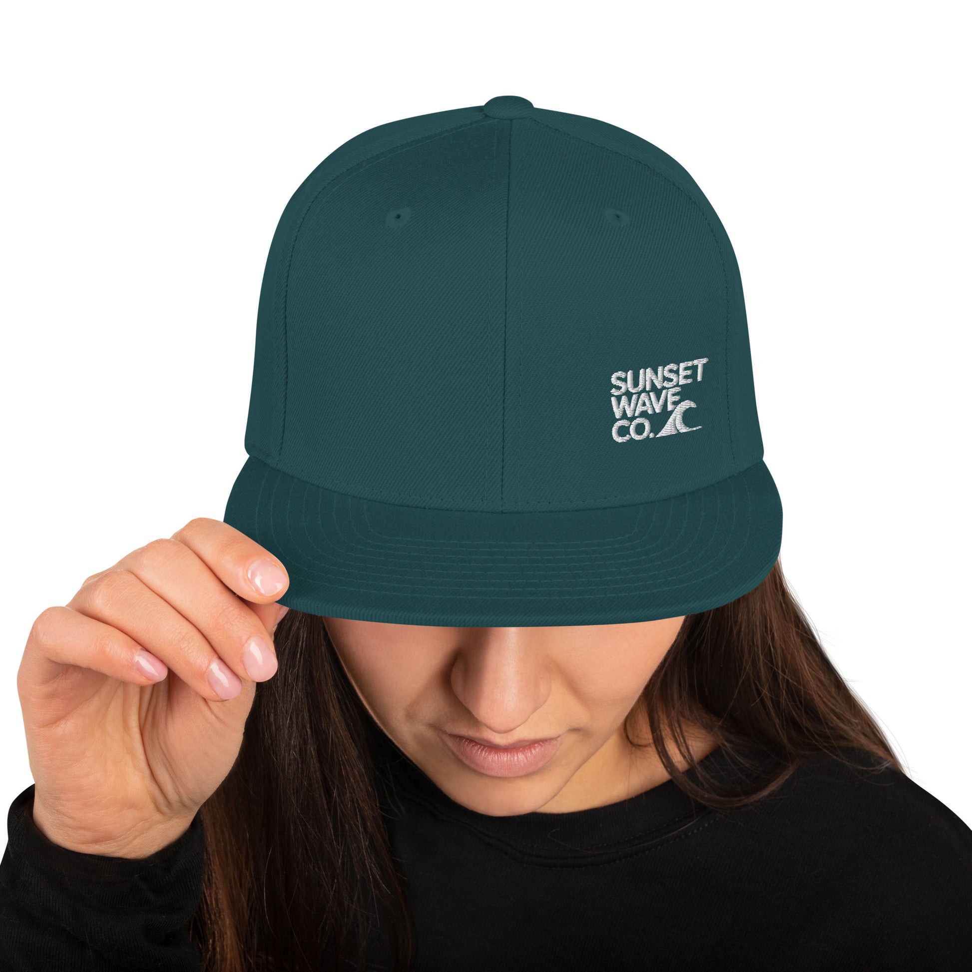 Woman wearing dark green classic snapback hat with white Sunset Wave Co. logo