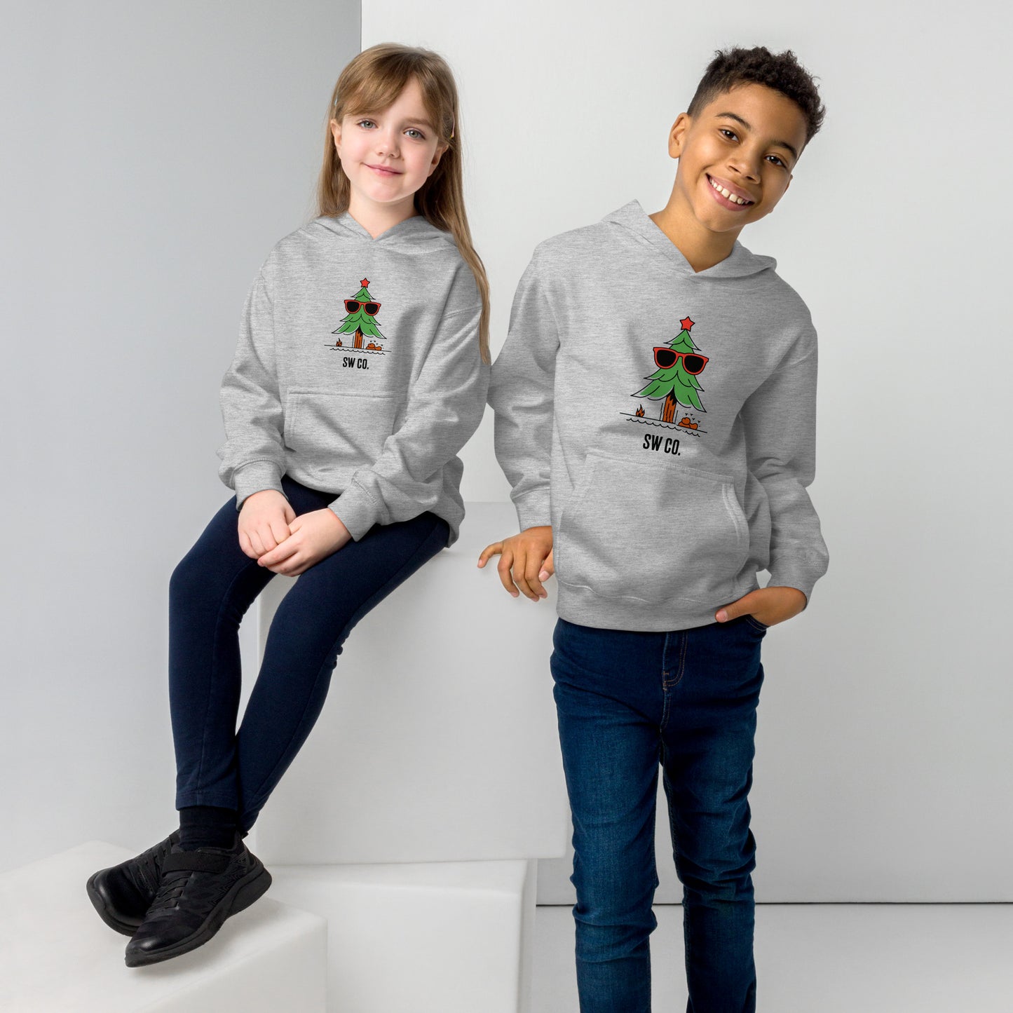 Two kids wearing athletic heather gray fleece hoodies with a cool Christmas tree design and SW CO. logo