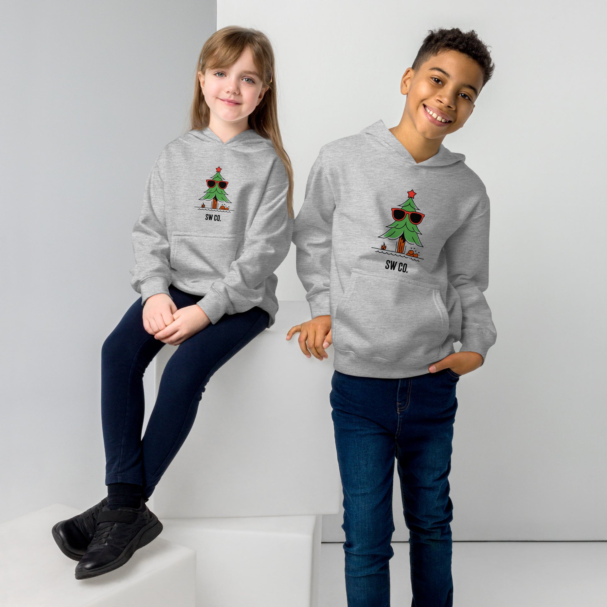 Two kids wearing athletic heather gray fleece hoodies with a cool Christmas tree design and SW CO. logo