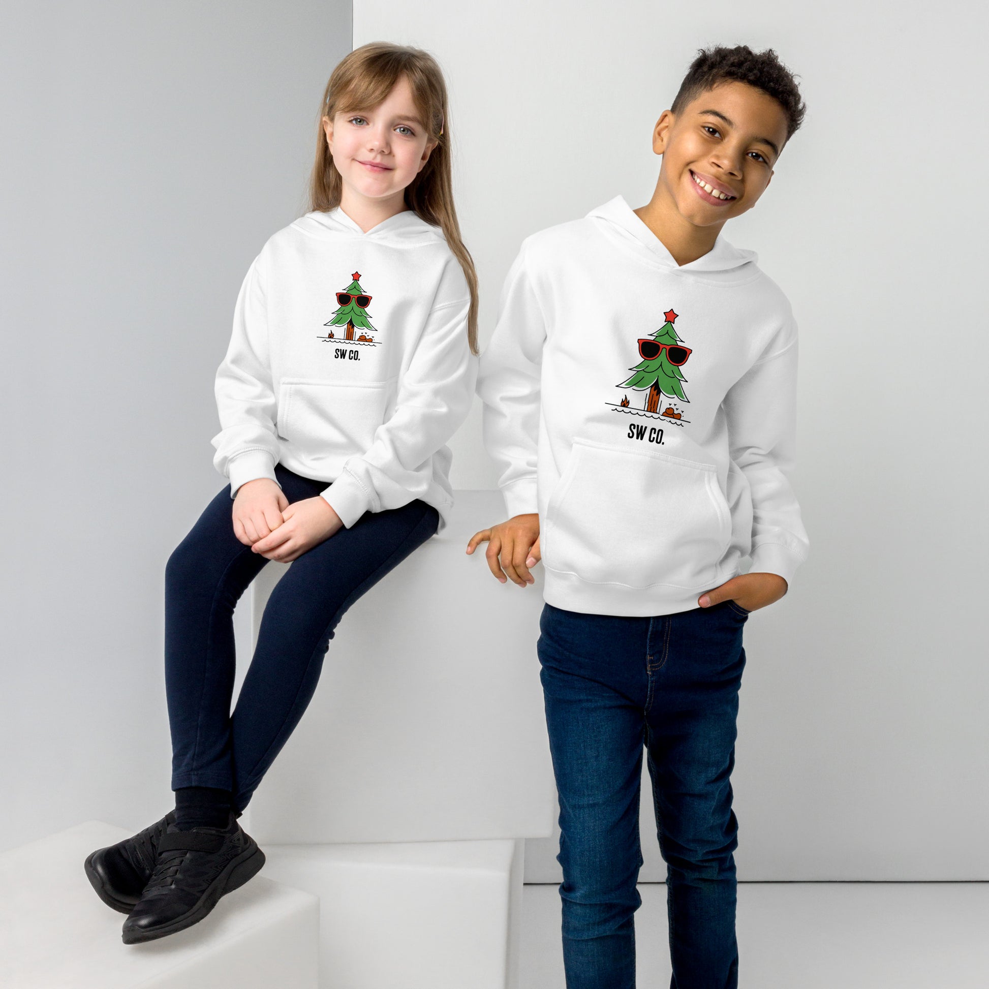 Two children wearing white fleece hoodies with sunglasses Christmas tree design, posing in studio