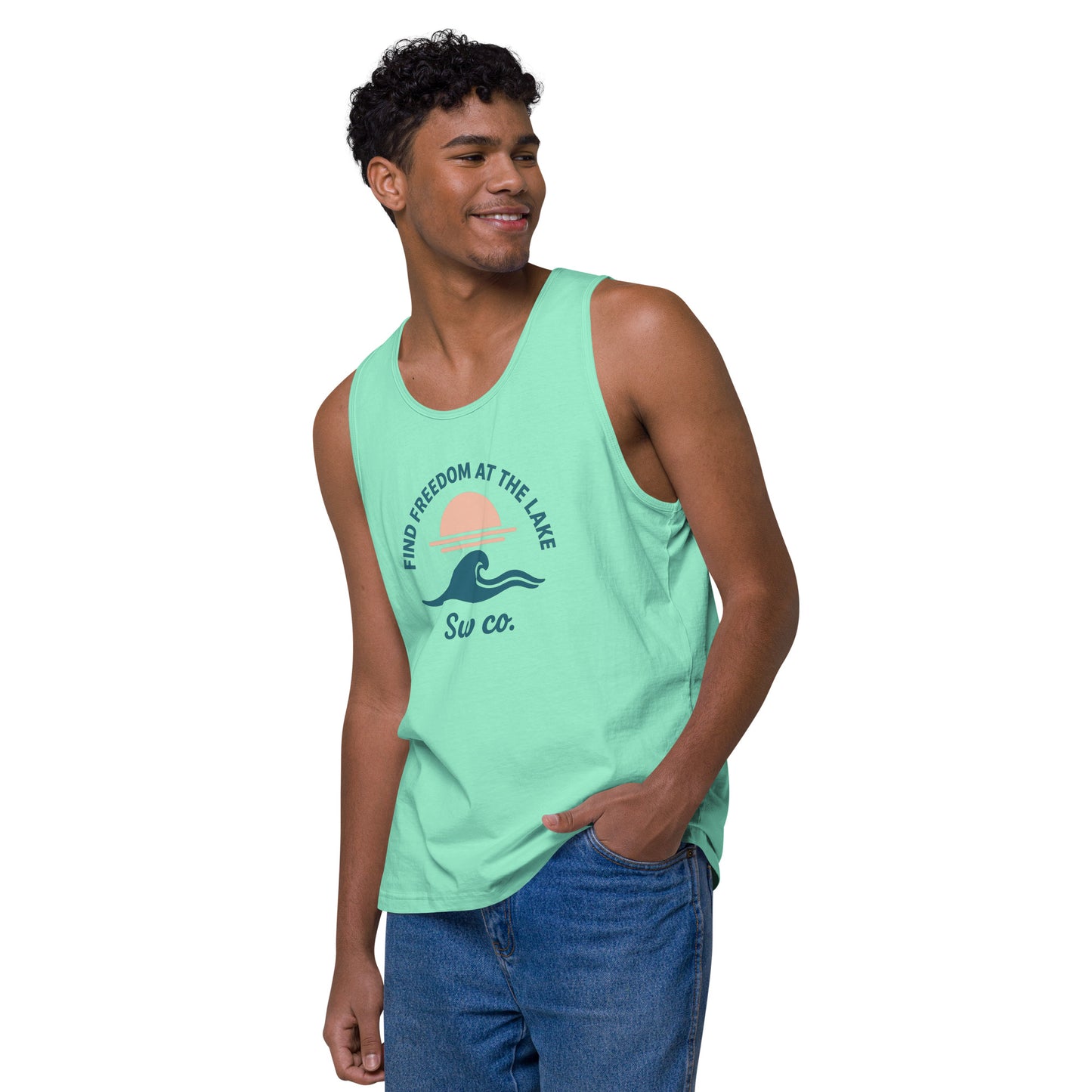 Man wearing mint green tank top with lake sunset and wave graphic, paired with blue jeans