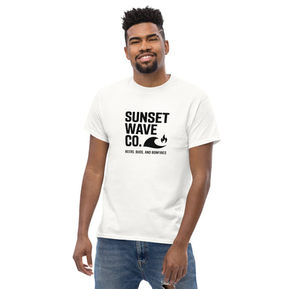 Smiling man wearing white Sunset Wave Co. graphic tee with wave and fire icons, paired with jeans
