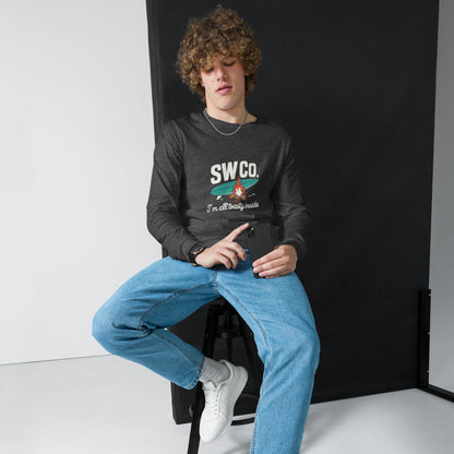 Young man wearing dark grey SWCo long sleeve tee with graphic, light blue jeans, white sneakers, holding smartphone