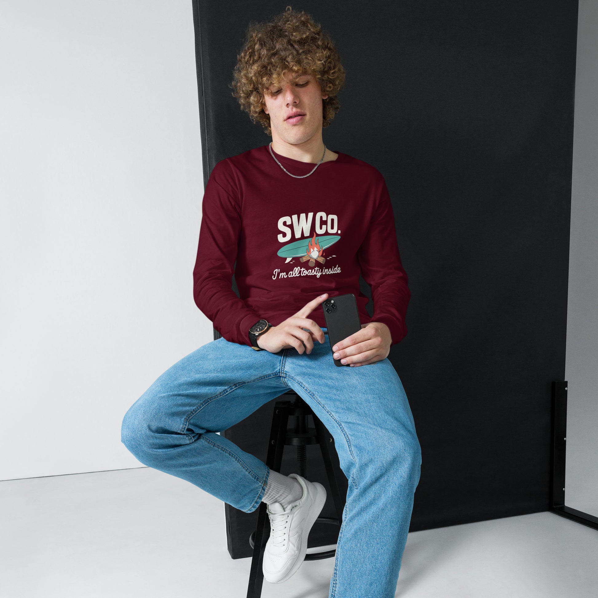 model wearing maroon unisex long sleeve tee with SWCo logo and toasty design, light blue jeans, white sneakers