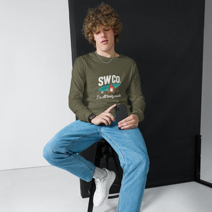Man wearing military green unisex long sleeve tee with SWCo logo and jeans, sitting on stool