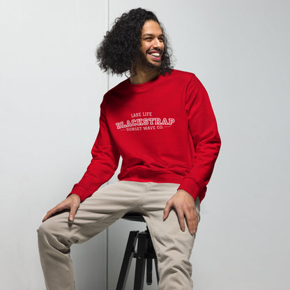 Smiling man sitting on stool wearing red Blackstrap Lake Life sweatshirt and beige pants