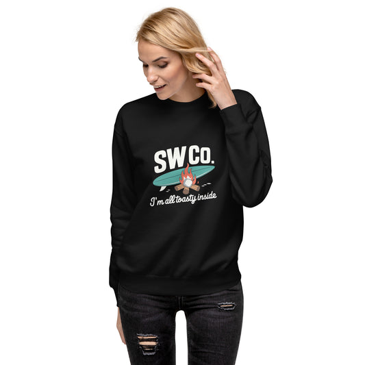 Blonde woman wearing black SW Co. sweatshirt with campfire and surfboard design, distressed black jeans